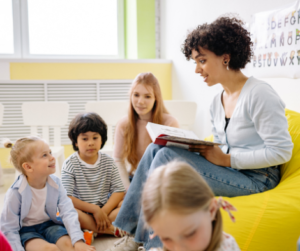 children sitting listening to a woman read a book